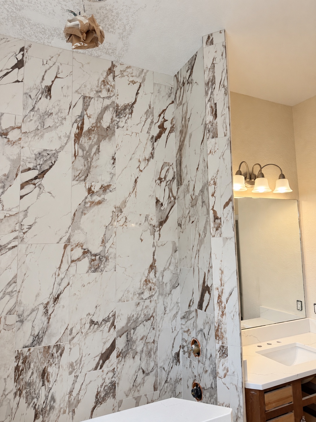 Marble-look shower wall beside a bathroom vanity during installation