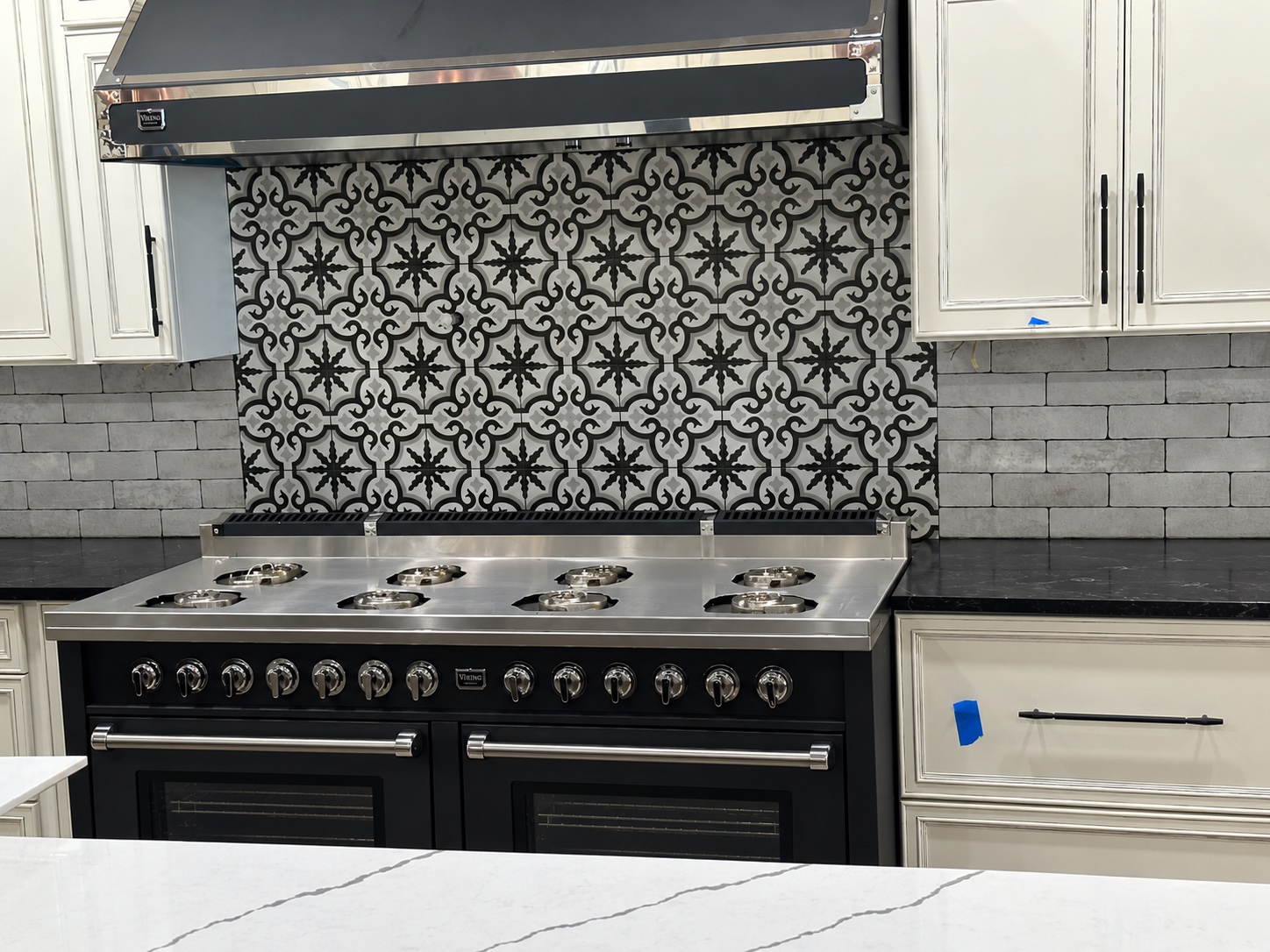 Black and white patterned kitchen backsplash behind a range during installation