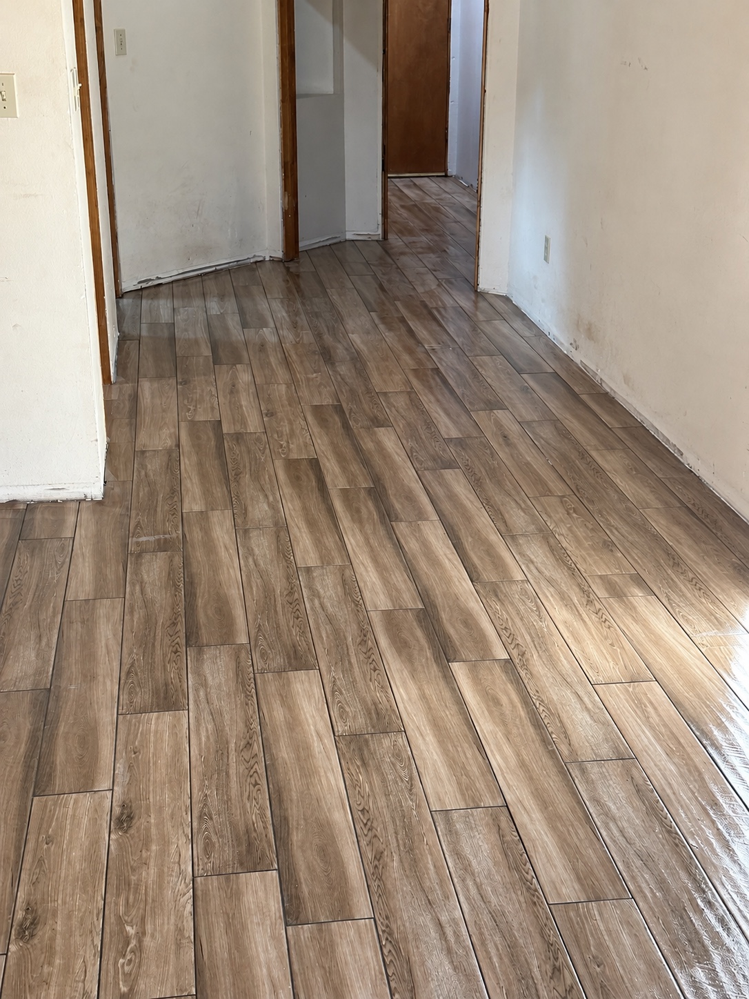 Wood-look tile flooring along a bright hallway during installation